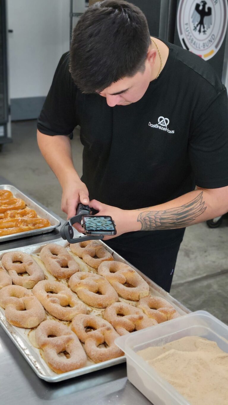 Brendon Bellerose doing videography in a bakery, focusing on freshly baked pretzels